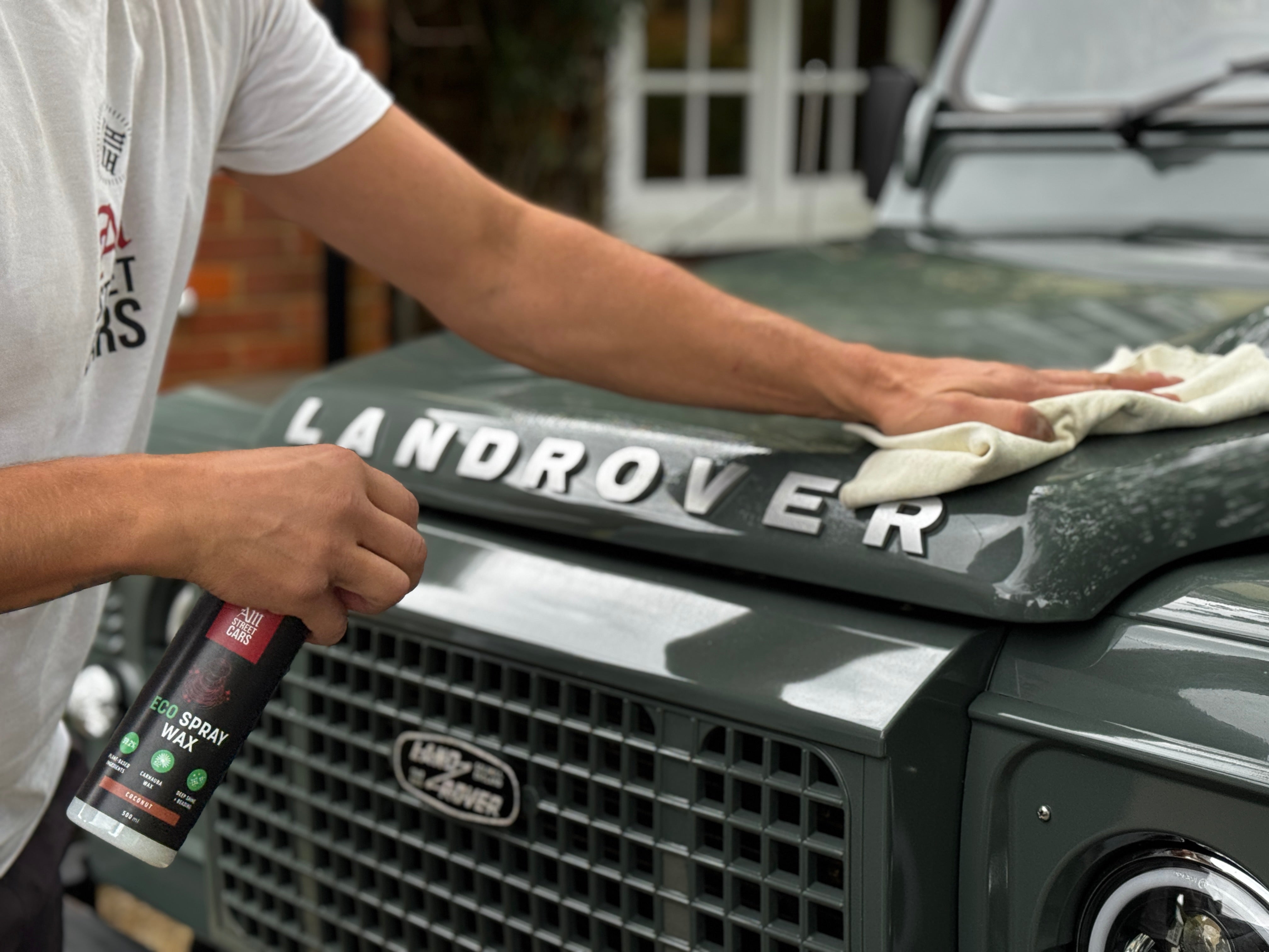 Person cleaning a Land Rover with a cloth and spray bottle.